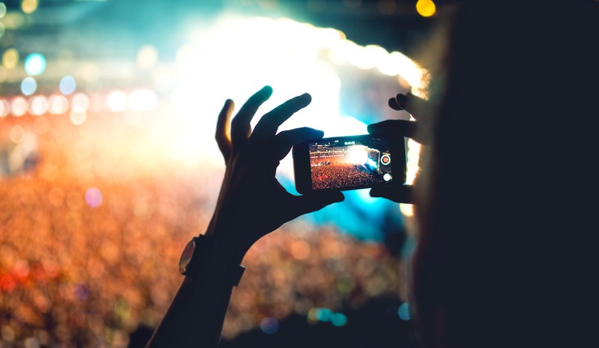 یک نفر در حال گرفتن ویدئو از یک کنسرت از جایگاه تماشاچیان برای صفحه اینستاگرام